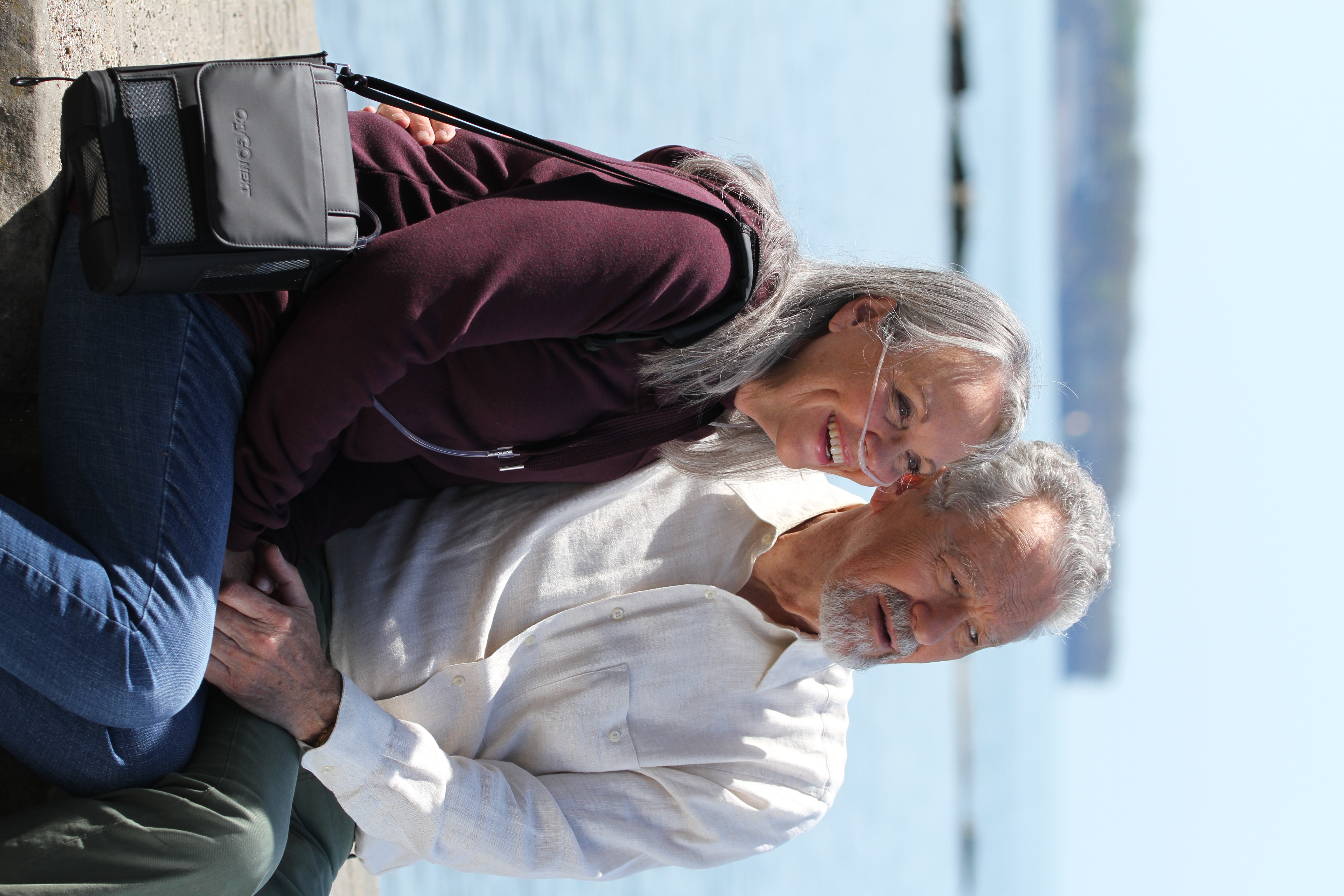 elderly lady and man sitting next to each other. lady is wearing oxygen